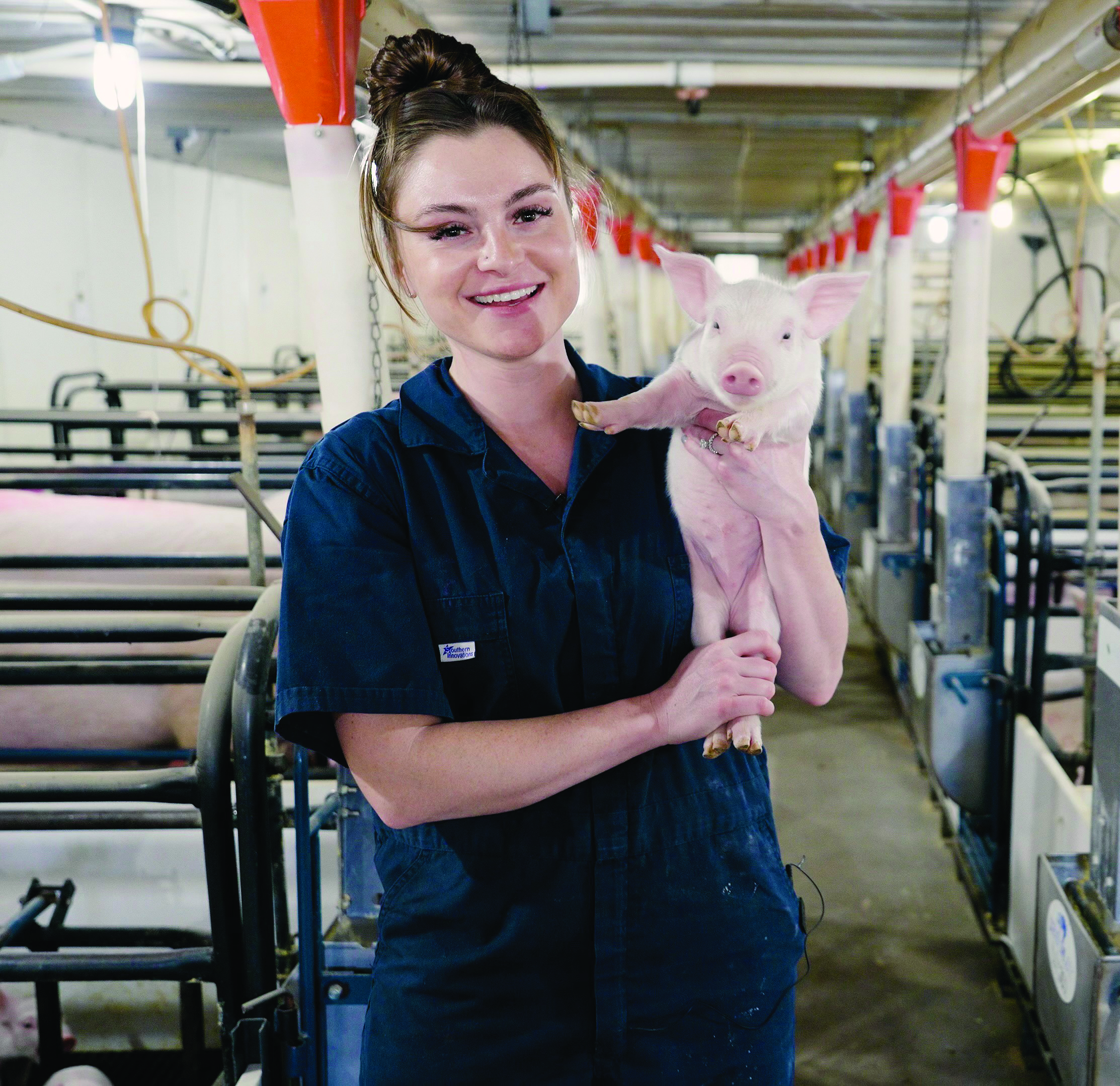Brooke Kitting '18 in a swine center with pigs around her.