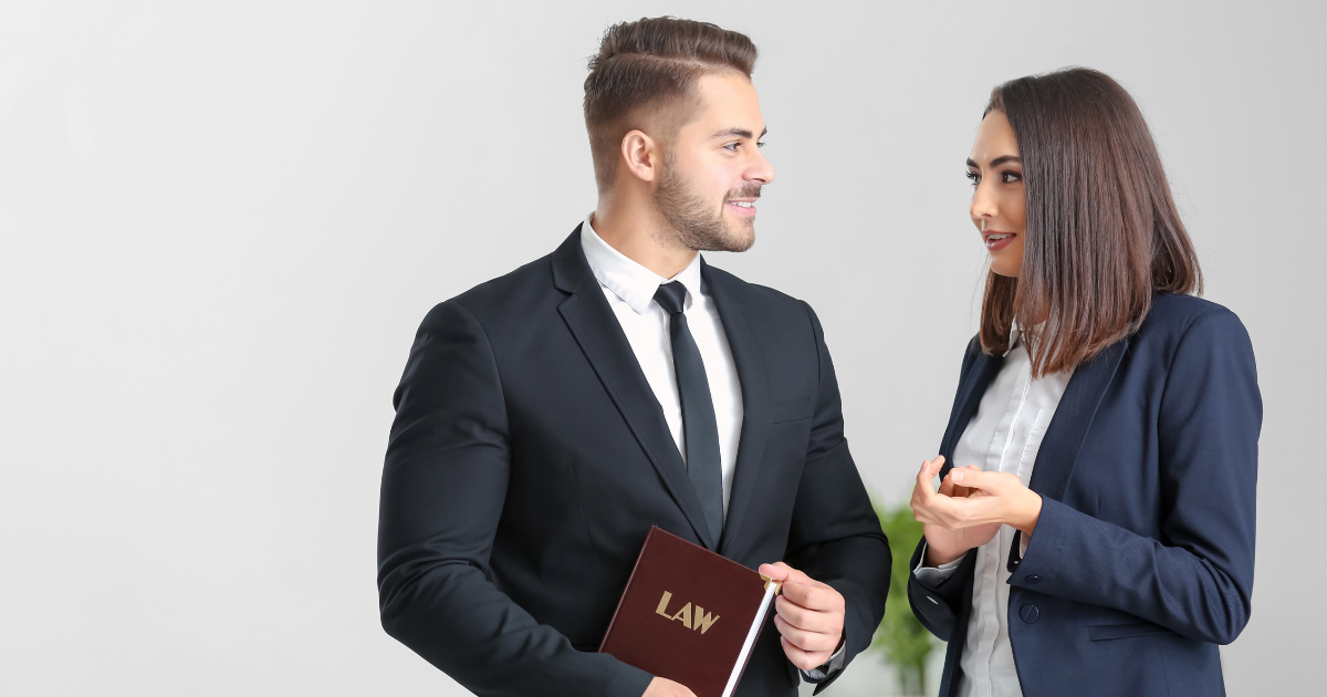 A male and female law professional in suits are speaking with another.