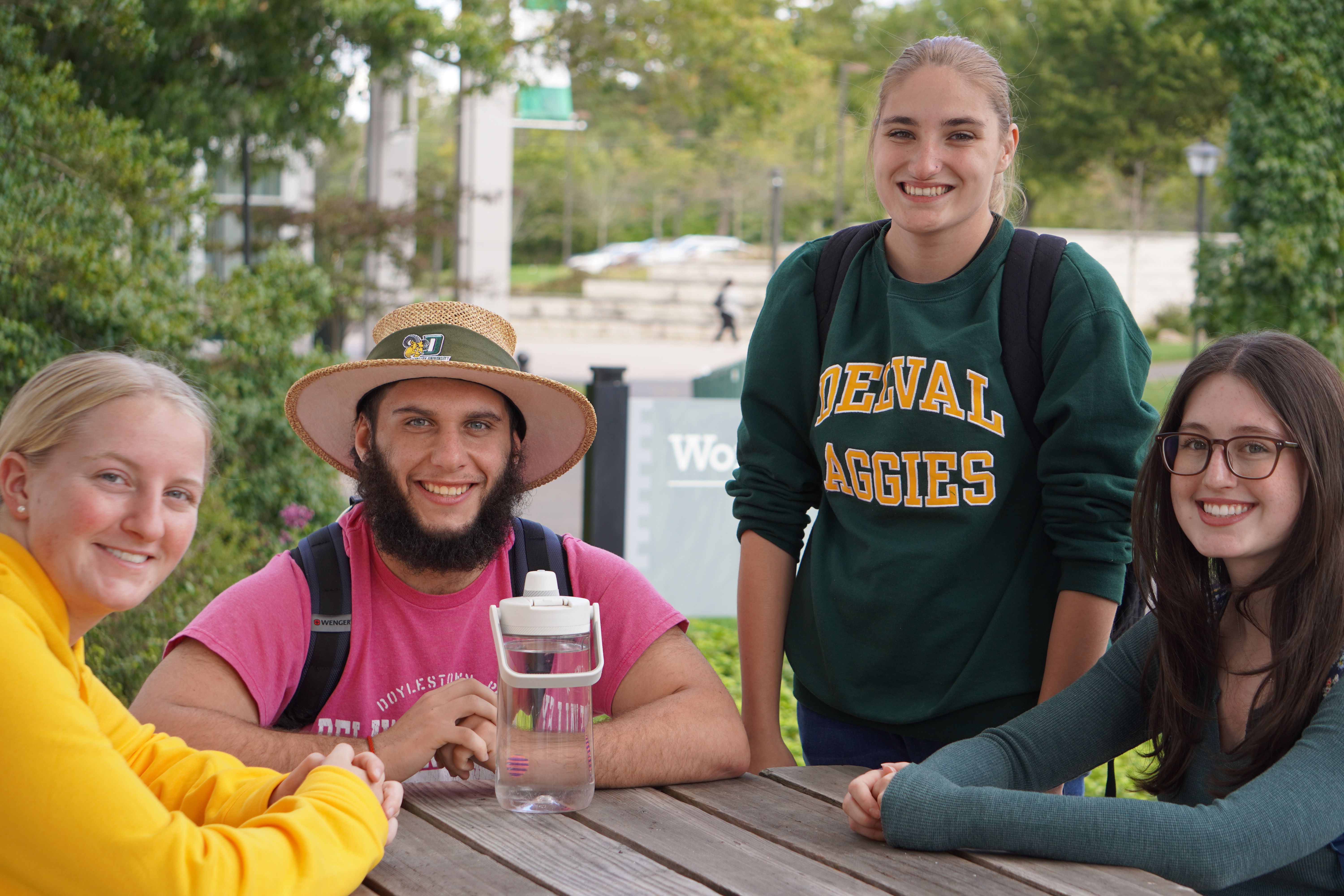 Four honors program students are seated at a bench, smiling at the camera. 