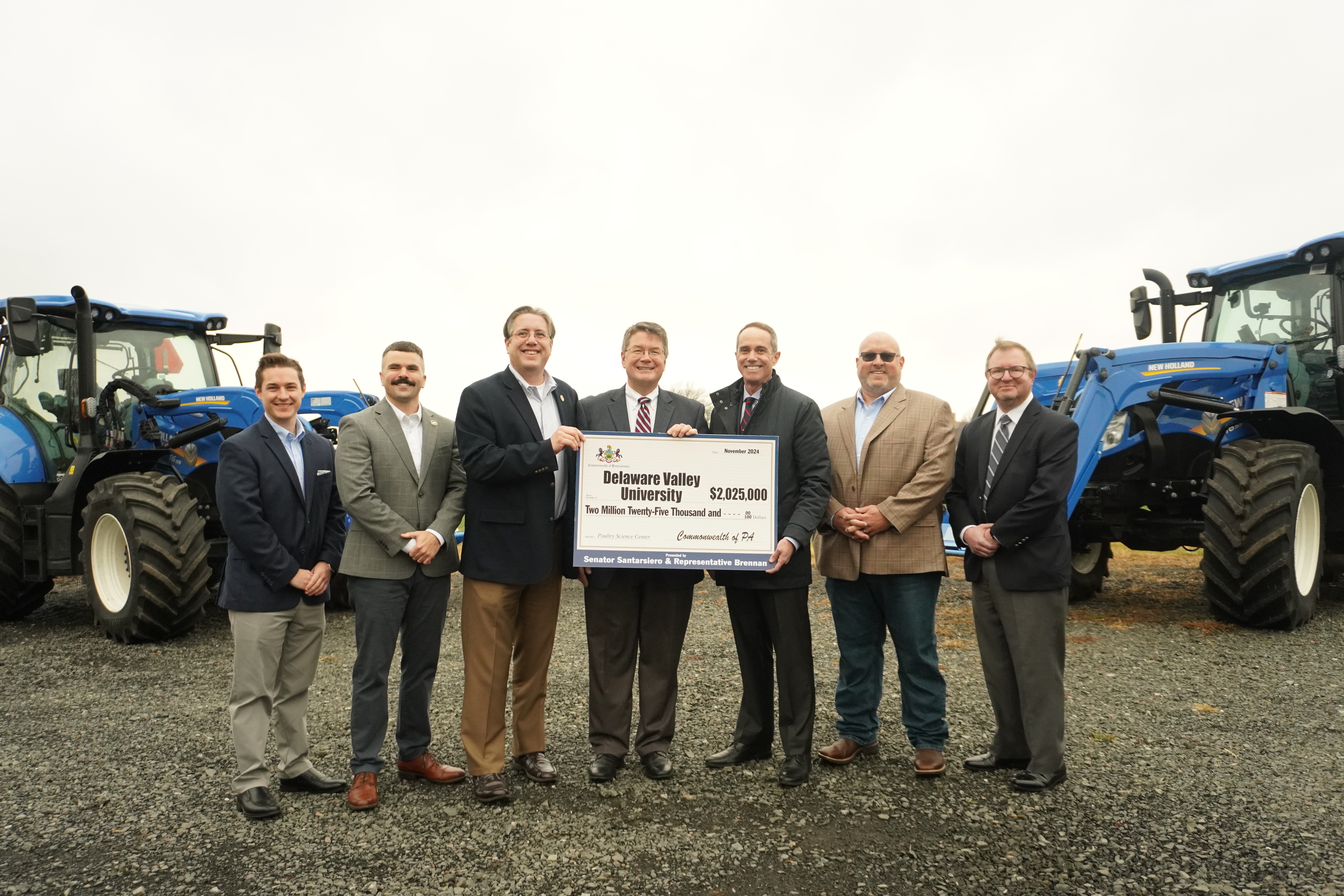 Group photo at the location of the new poultry science center holding a giant check.