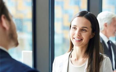 A close-up photo of a young professional woman speaking with a young professional man.