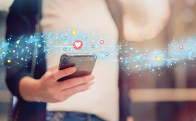 someone holding a phone with social media icons floating above.