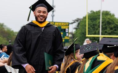 A student is walking to their seat after receiving their diploma at commencement.