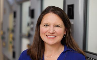 Melissa Langston in the lab for a headshot wearing a blue collared shirt. 