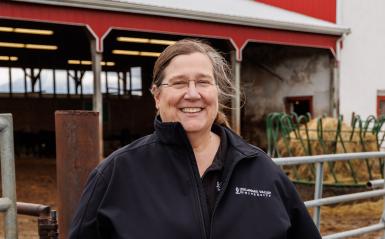 Joanne Powell headshot by the dairy barn, wearing a black delval zip up jacket. 