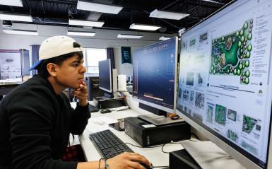 A landscape design/build major is creating a landscape digitally on a computer.
