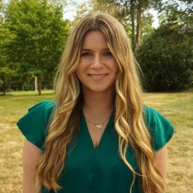 A headshot of Maggie Brown in front of the admissions cottage.