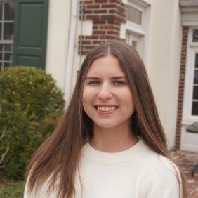 Jessica Ellick outside of the admission cottage smiling at the camera for a headshot. 