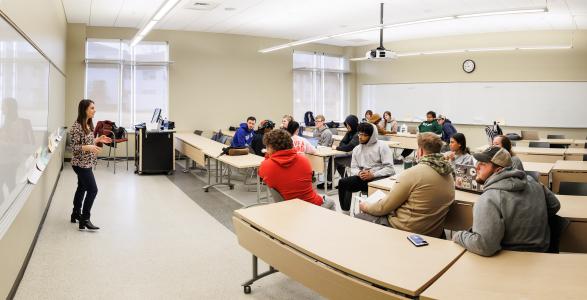 A wide image of a professor teaching in a classroom. 