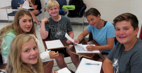 Students collaborating at desks at an Inspire U! teens course with a professor. 