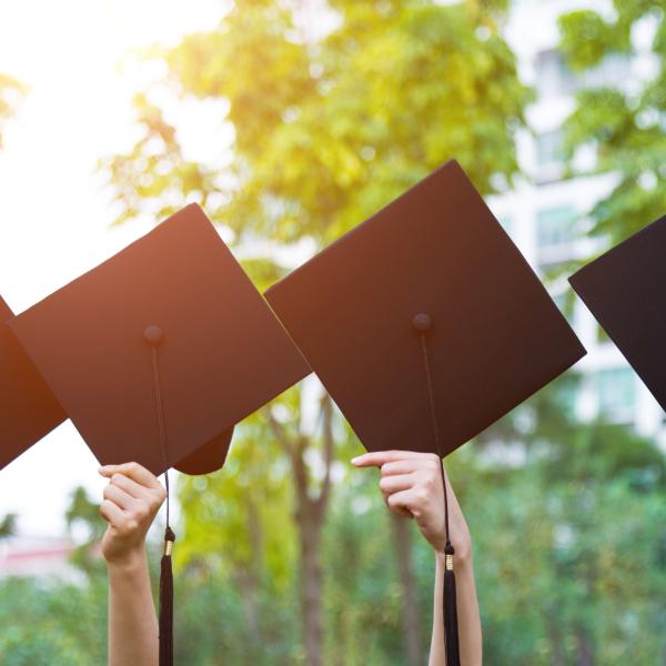 Hands holding up graduation caps