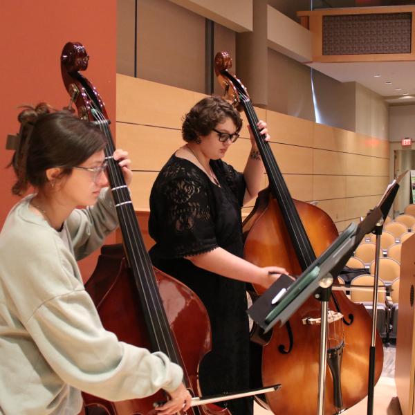 Students are playing instruments on stage at the Life Sciences Building Auditorium.