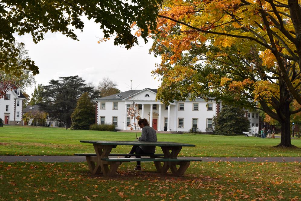 Student sits at park table near campus building