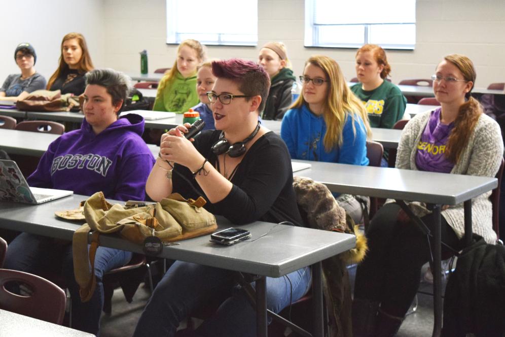 A student is speaking into a microphone in rock music history class. 