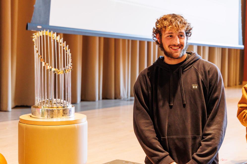A student is taking a photo next to a gold phillies award. 