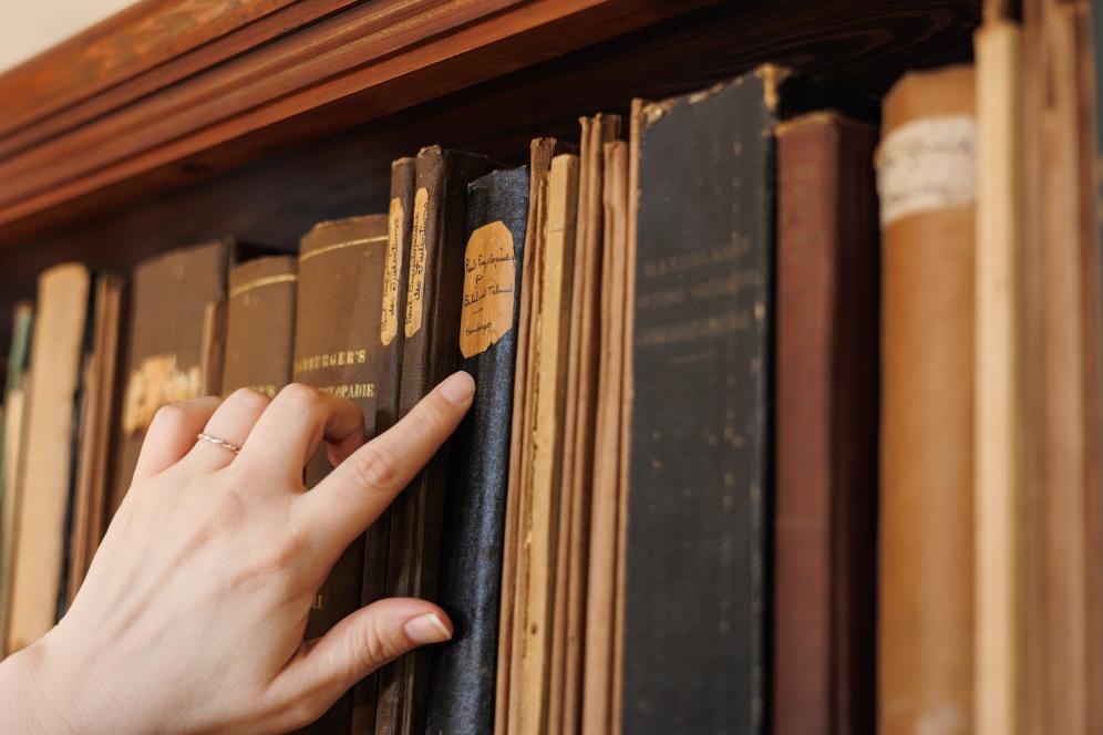 Claire Drolet is pointing at a book on the shelf in the library. 
