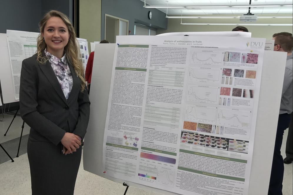 Diana Rachii, a student, is standing beside her research poster.