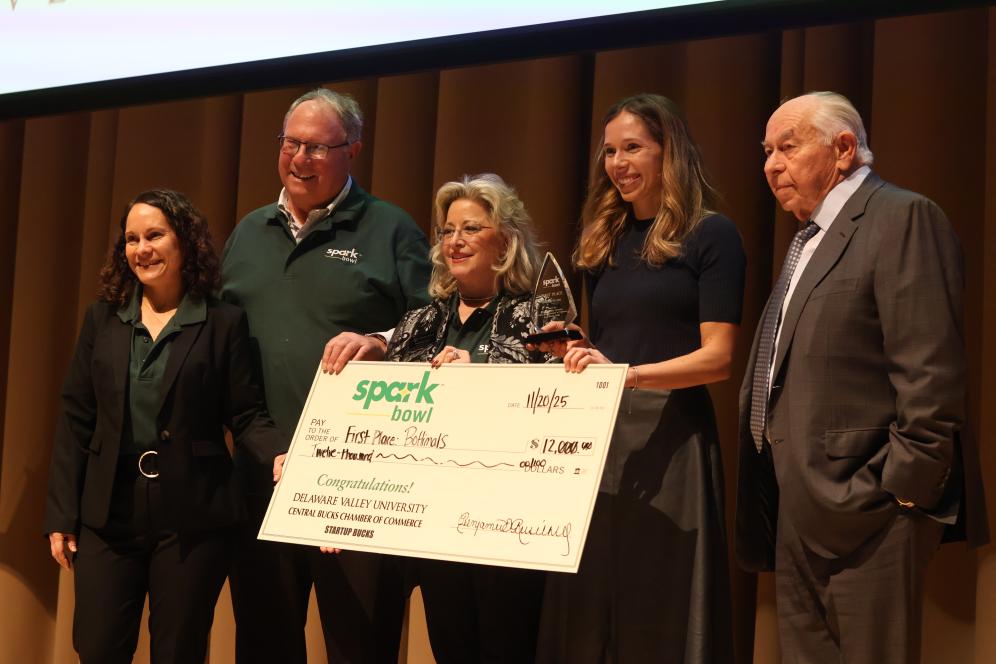 Spark Bowl first place winner, Bottimals is on stage receiving a giant check. 