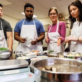 three students and a professor are in the food science lab talking 