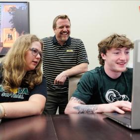 Jeff Wehrung, professor, is working with students in a conference room.