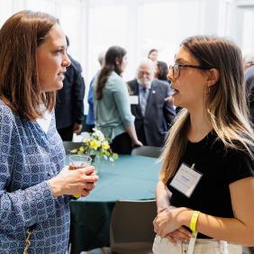 Two Women in business attire are networking at an event in the life sciences building. 