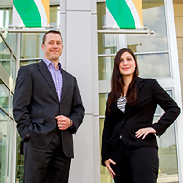 A man and women stand in front of DVU flags