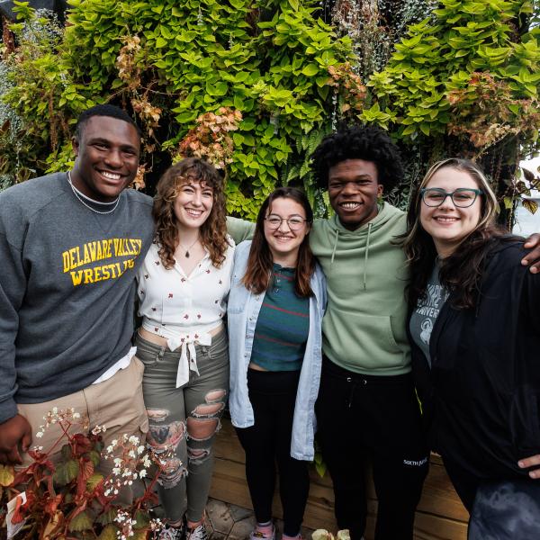 Terrain Students in a group photo with a flower wall behind them. 