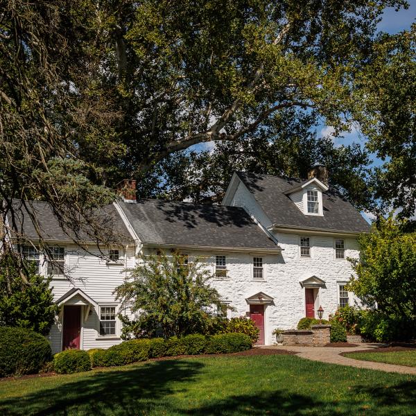 A photo of the presidents house on campus loop rd, surrounded by trees and bushes. 