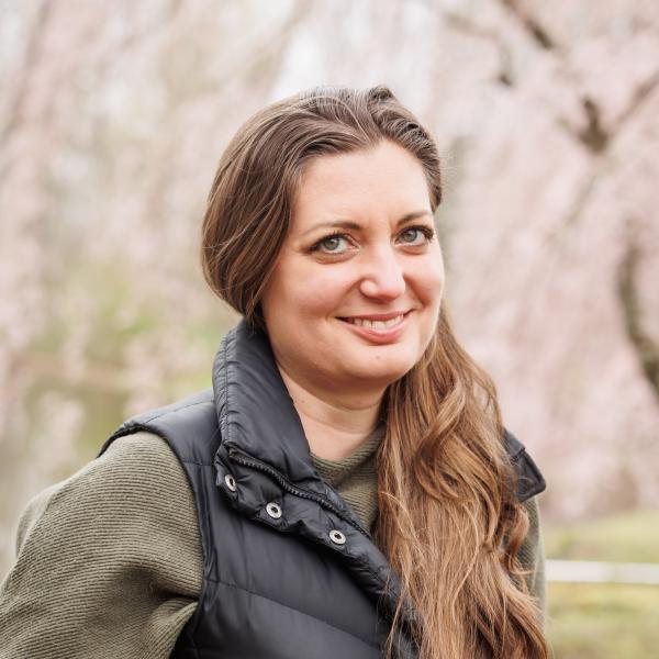 A headshot photo of Kimberly Reichner at lake archer wearing a black vest with an olive green long sleeve shirt underneath. 
