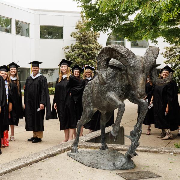 Graduates are lined up behind the Caesar Ram statue. 