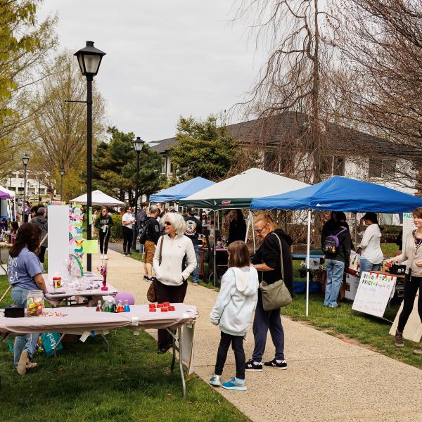 Vendors tents are lined up outdoors on the quad. 