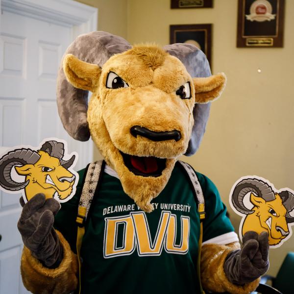 Caesar is holding two printed cutouts of the mascot. 