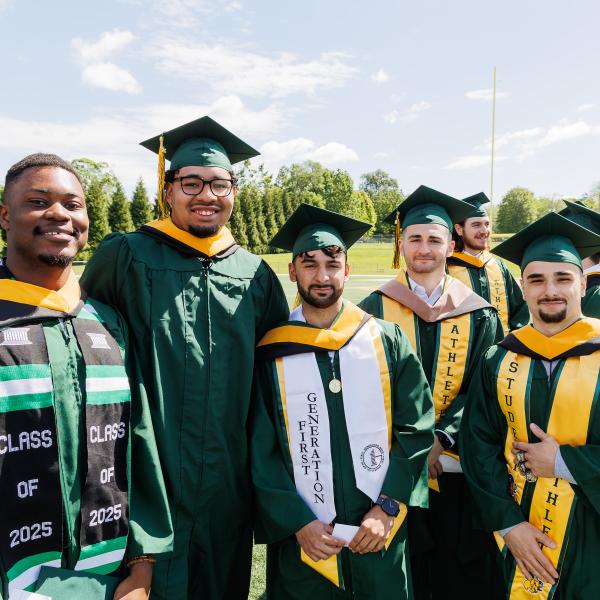 Four male students from the Class of 2025 are posed for a photo at commencement wearing regalia. 