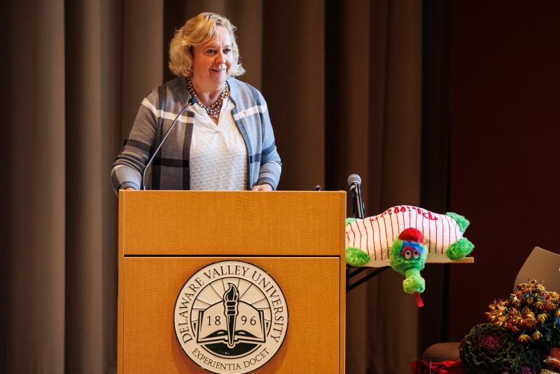 Kathy Killian standing behind a podium on stage in the Life Sciences Building. 