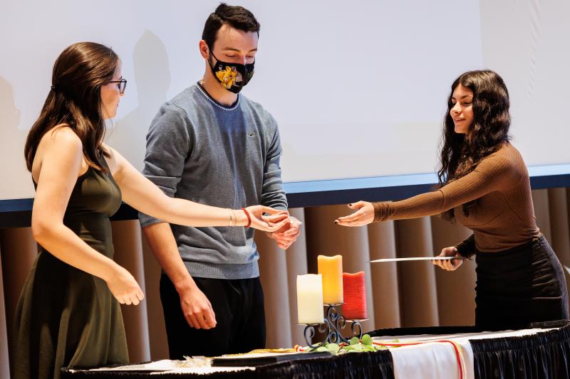 A students grabs an honor society pin from the honor society president on stage. 