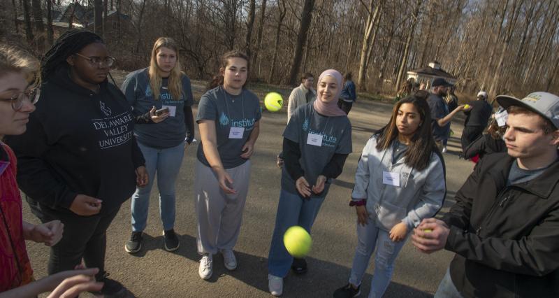 Students are playing a ball game in groups outdoors.