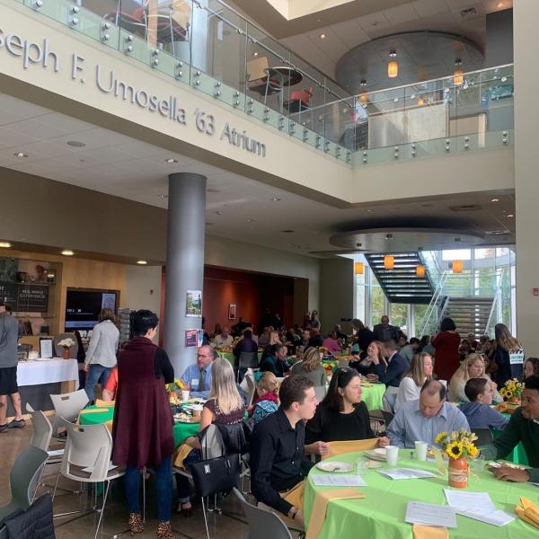 Alumni seated in the atrium at round tables. 