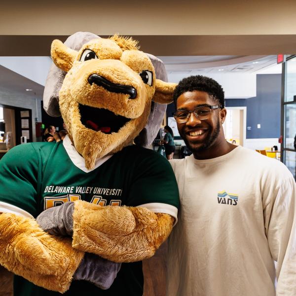 A student is smiling with Caesar in the dining hall. 