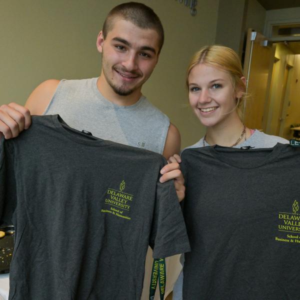 Students from the school of business and humanities hold up free tshirts. 