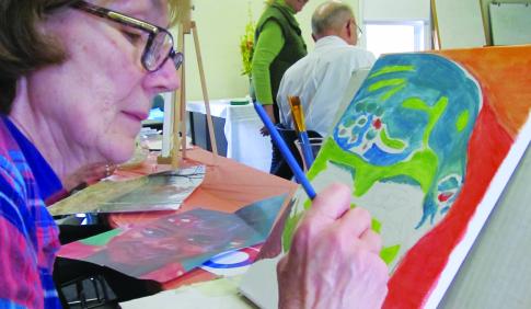 Senior student painting in a classroom