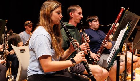 Four students playing the flute and reading sheet music in the auditorium. 