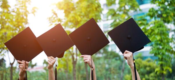 Four graduation caps being head up by their corners.