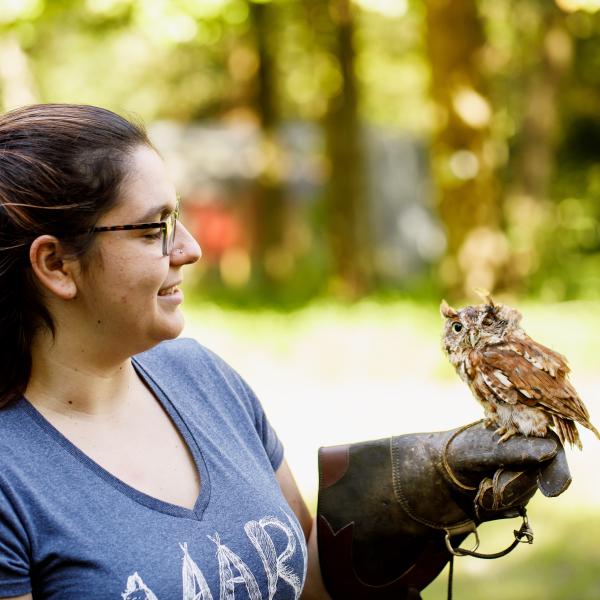 A female student is handling an owl. 
