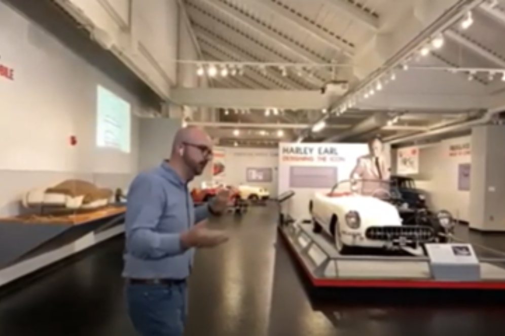 A man is giving a tour at a car showcase. 